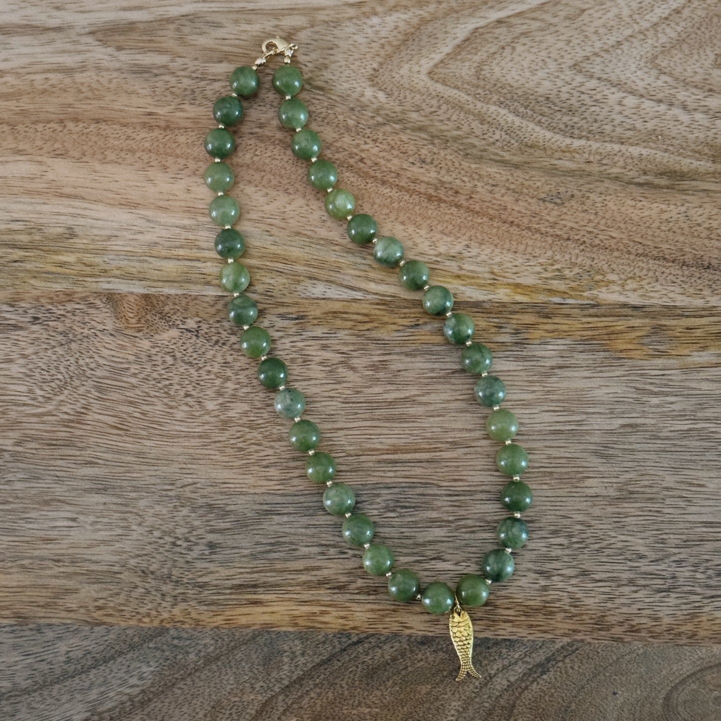 green and gold beaded necklace with brass fish charm and gold lobster clasp