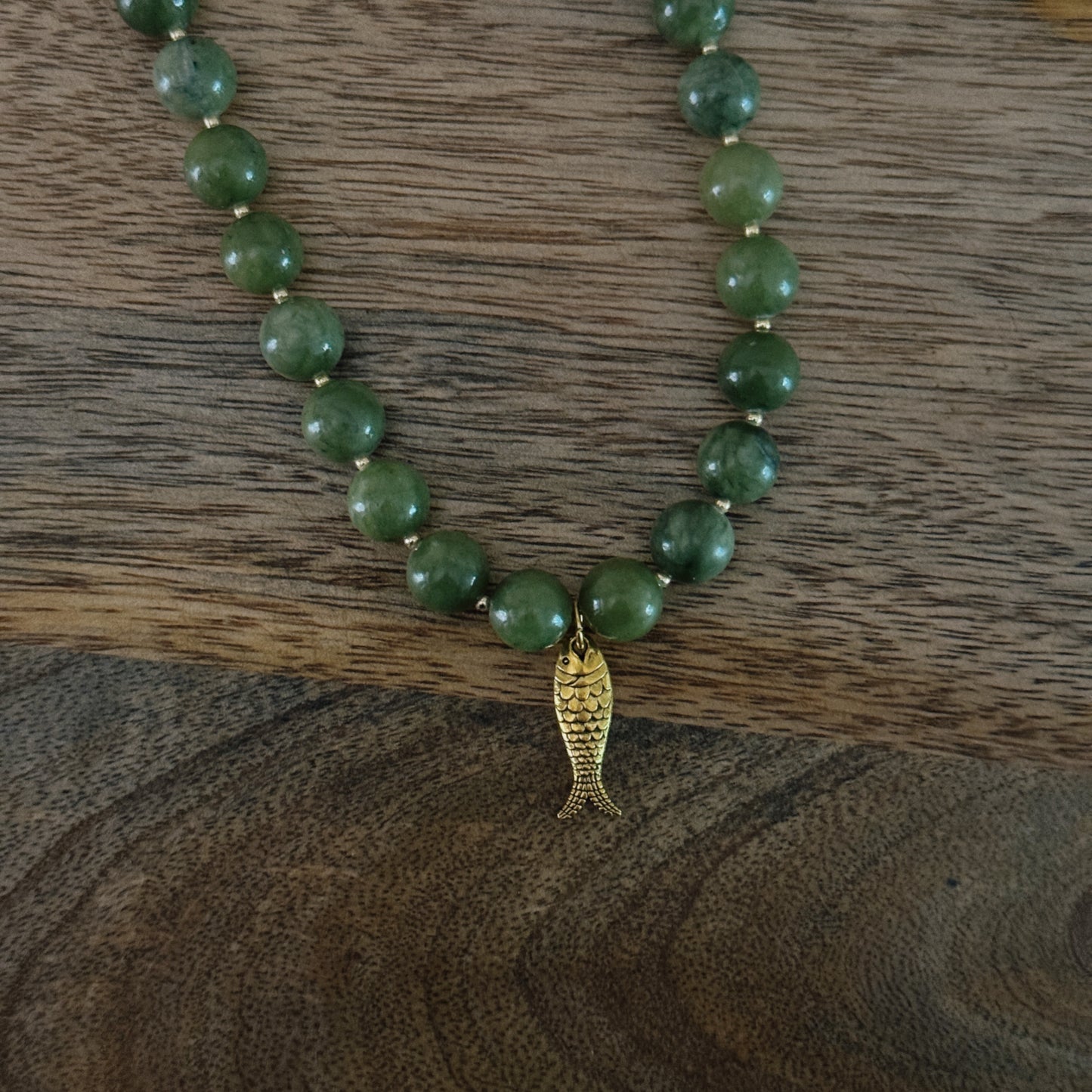 green and gold beaded necklace with brass fish charm and gold lobster clasp