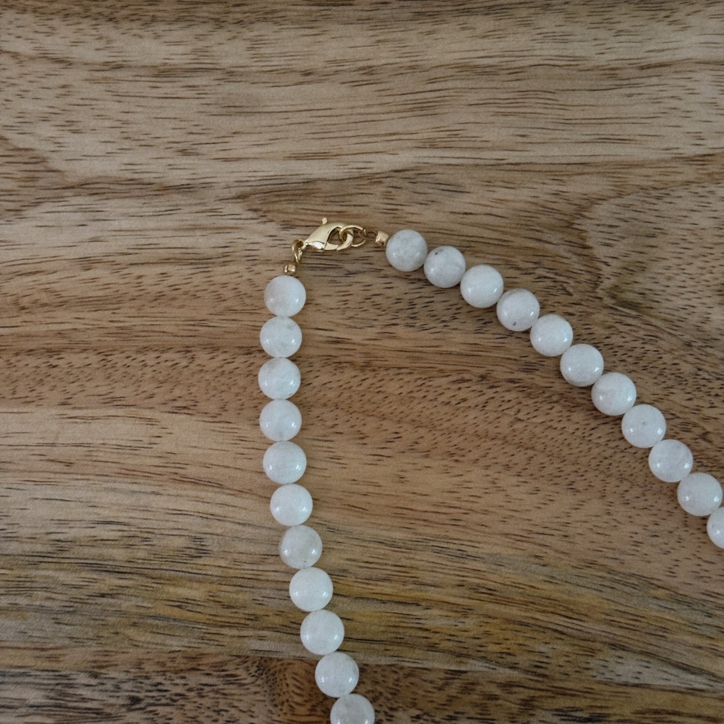 white glass beaded necklace with brass heart charm with horseshoe and "good luck" and 18k gold filled lobster clasp