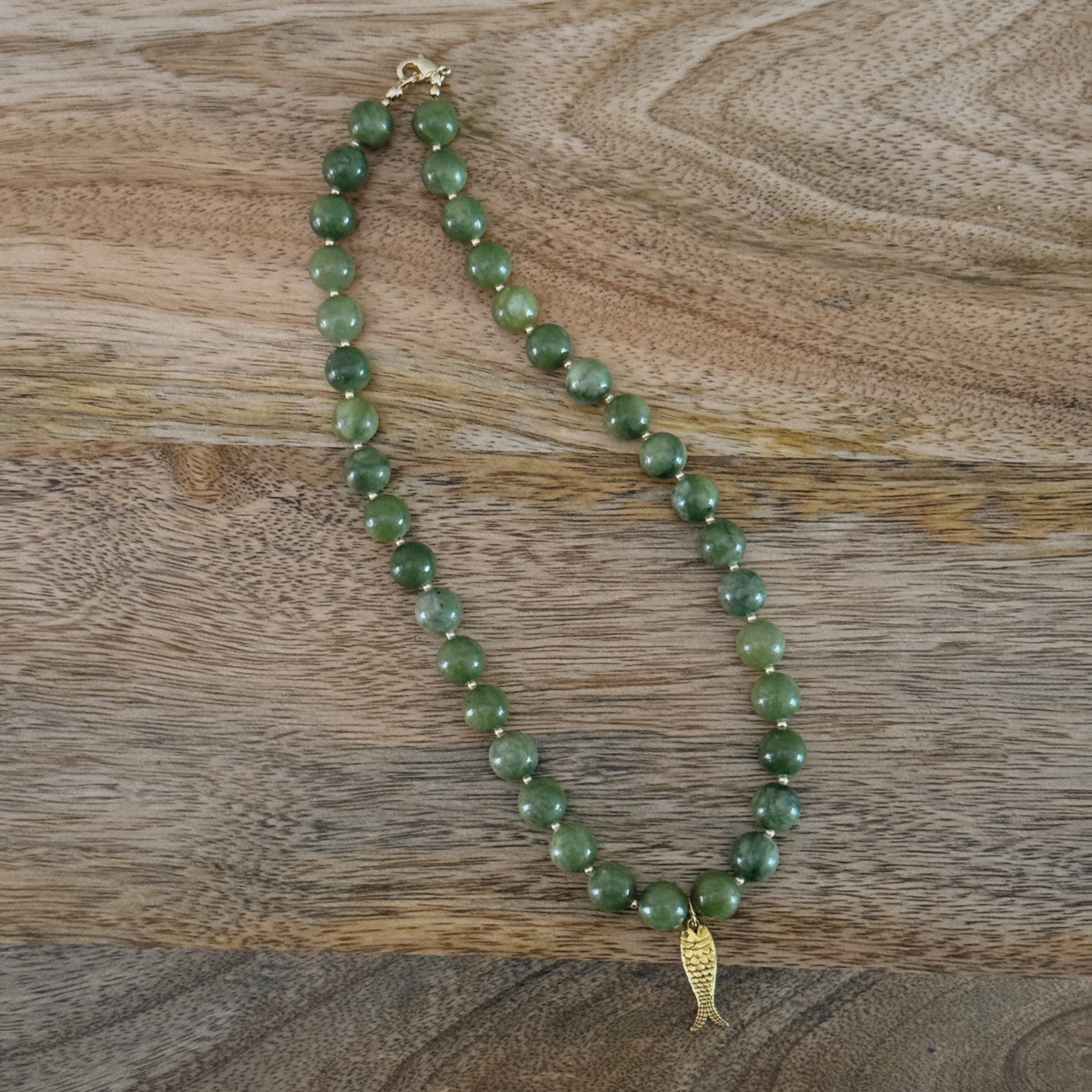 green and gold beaded necklace with brass fish charm and gold lobster clasp