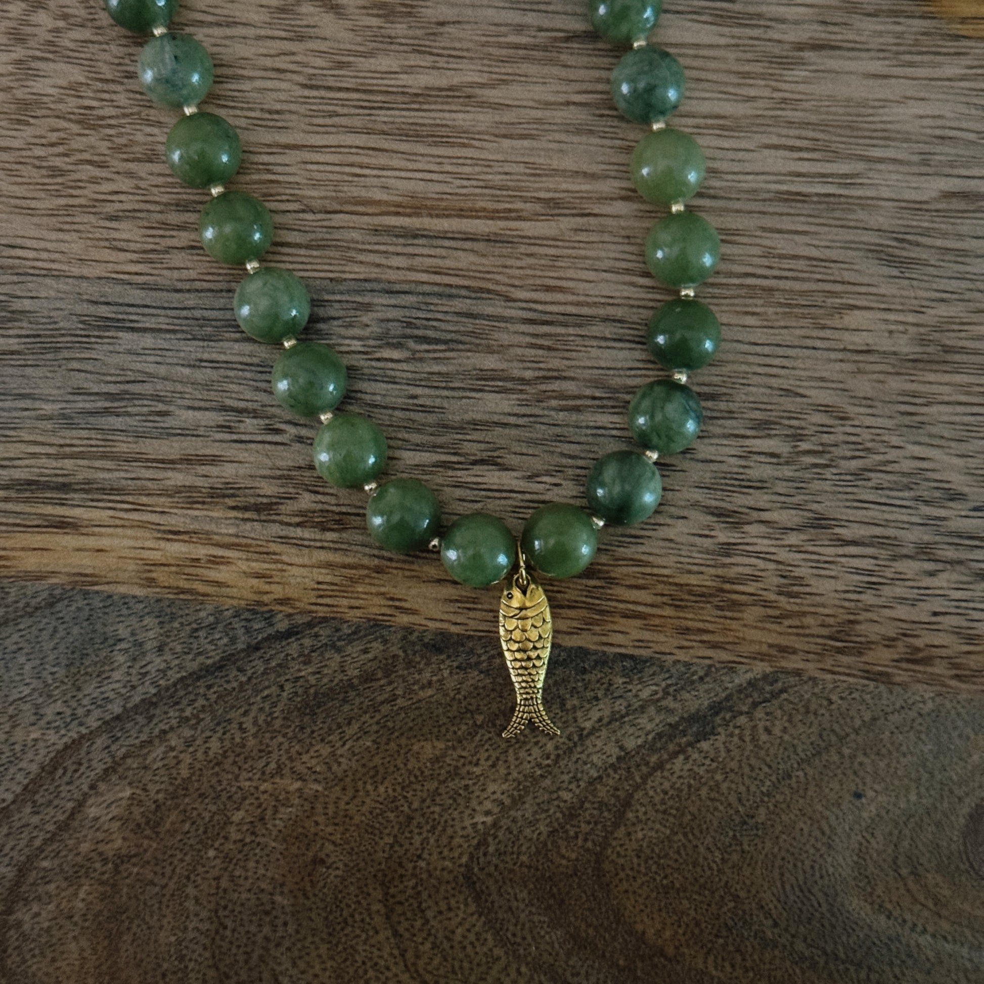 green and gold beaded necklace with brass fish charm and gold lobster clasp