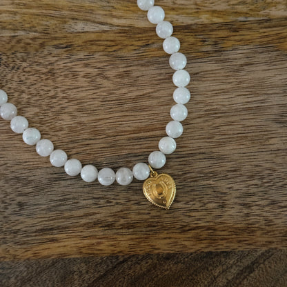 white glass beaded necklace with brass heart charm with horseshoe and "good luck" and 18k gold filled lobster clasp
