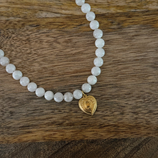 white glass beaded necklace with brass heart charm with horseshoe and "good luck" and 18k gold filled lobster clasp