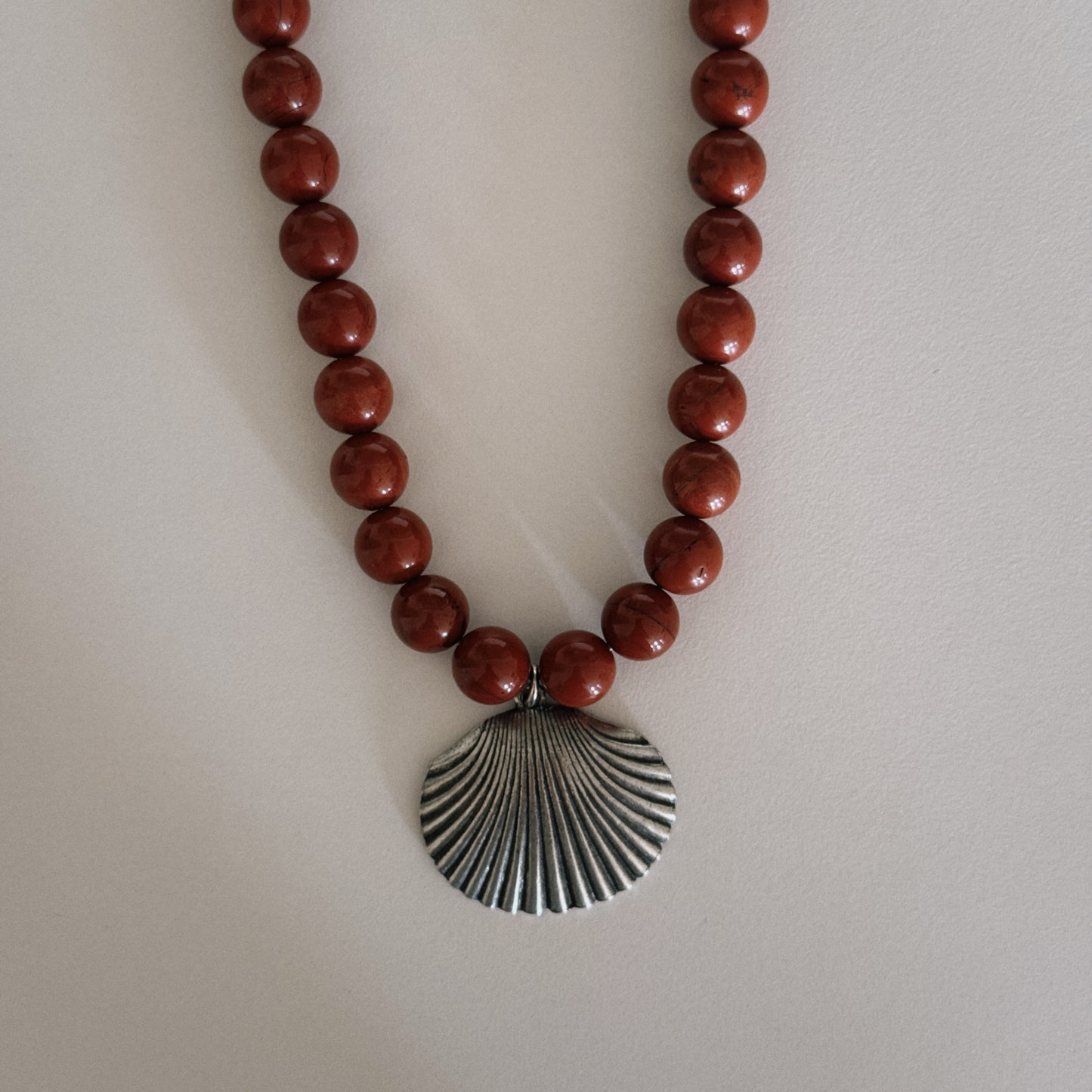 red beaded necklace with shell pendant